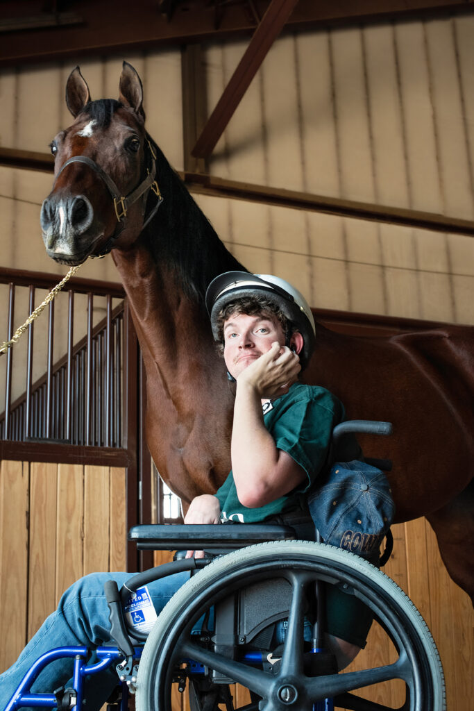 Boy in a wheelchair next to a horse.