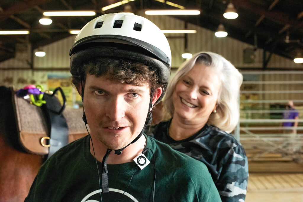 A boy in a helmet with a woman behind him.