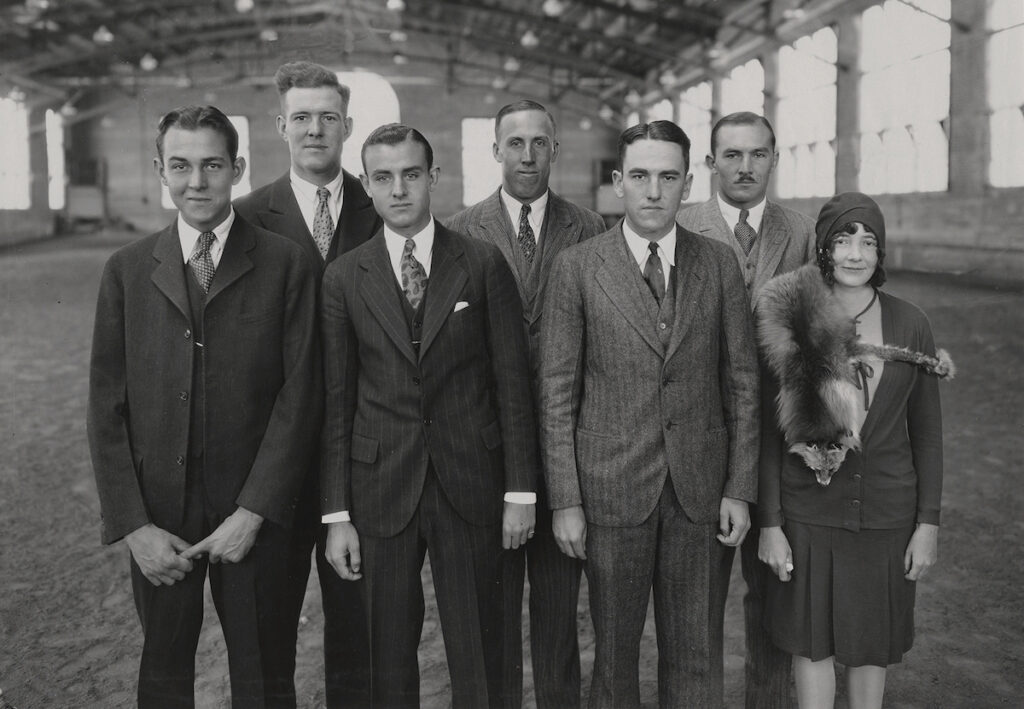 Black and white photo of seven people in suits and dresses.