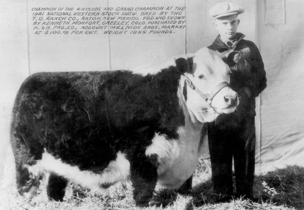 Black and white photo of a boy with a cow.