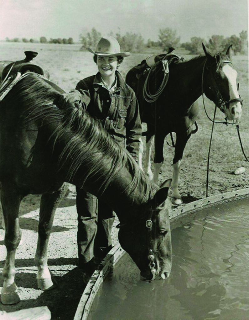 Black and white photo of a woman with two horses.
