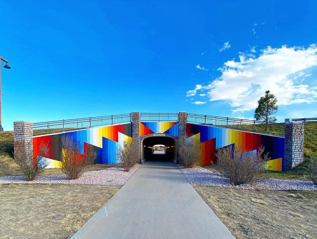 Bridge over a cement path painted in bright blues, reds, and yellows.