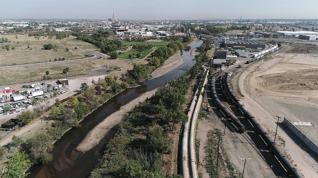 Aerial view of large sewer pipes running alongside a river.