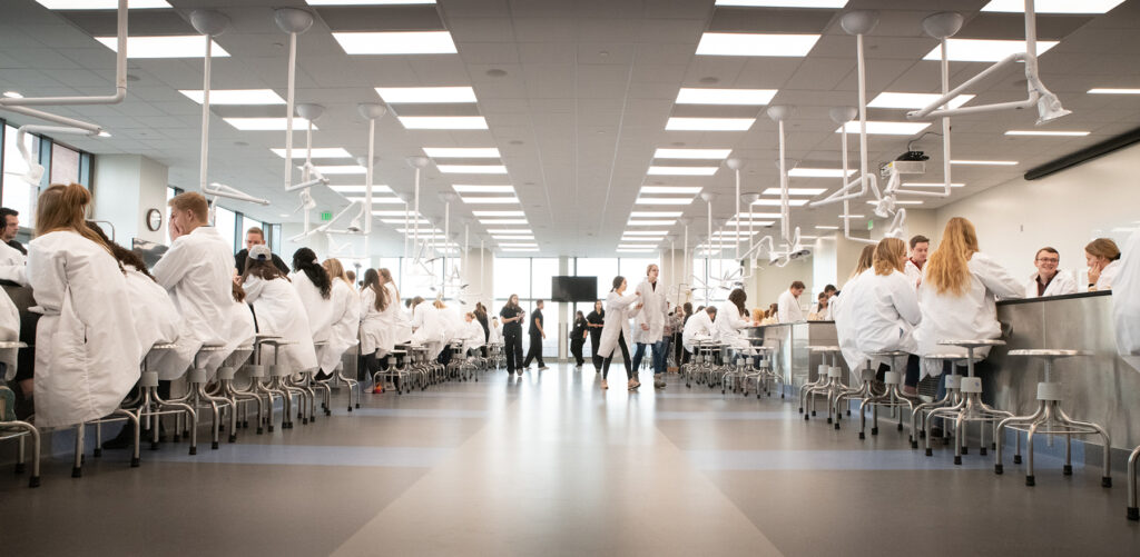 Rows of students at lab tables in white coats.