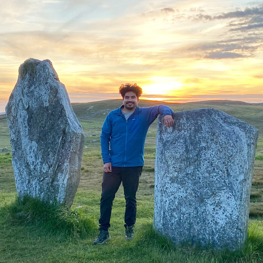 Man standing between two rocks at sunset.