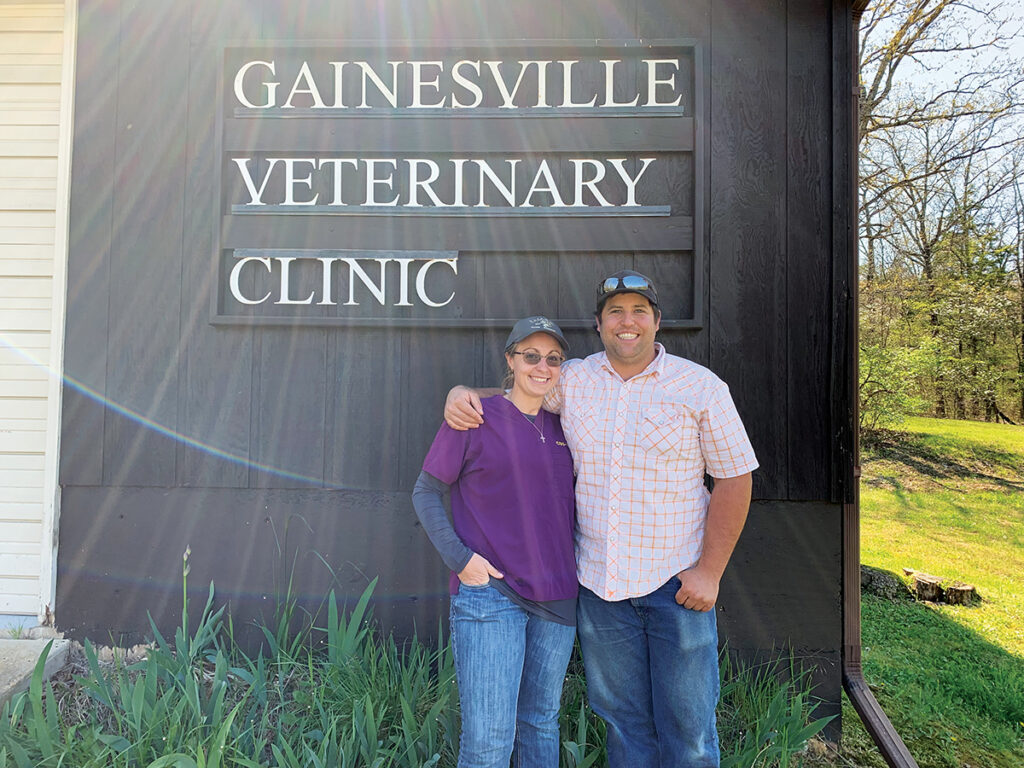 Two people stand in front of a sign that says Gainesville Veterinary Clinic.