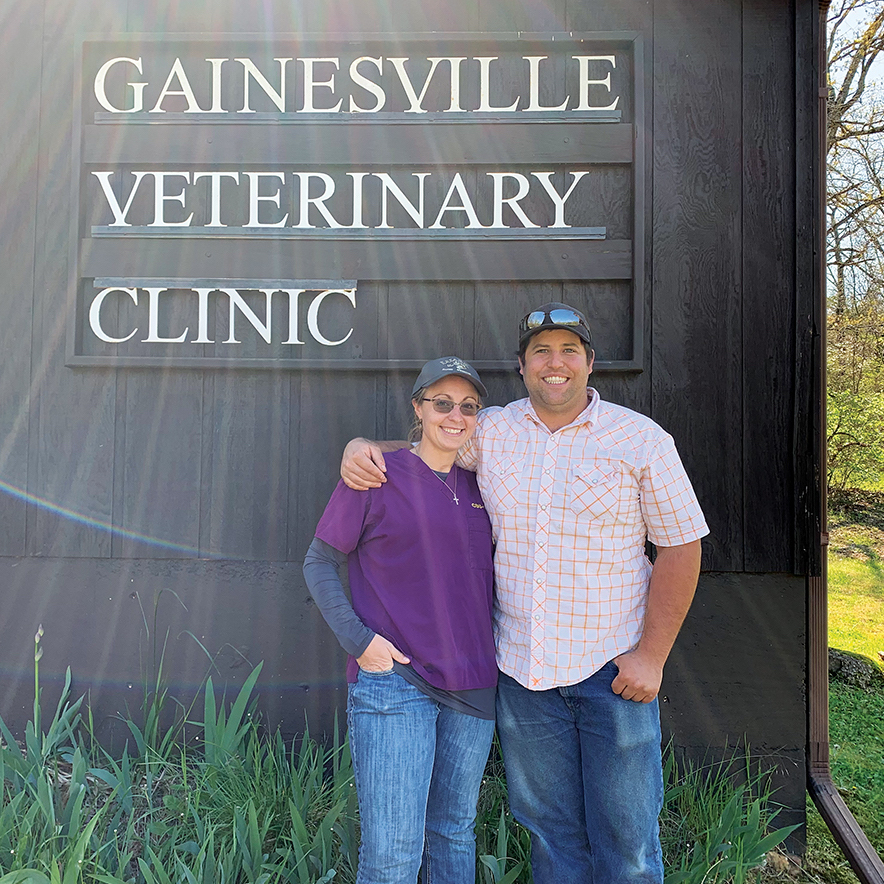 Two people stand in front of a sign that says Gainesville Veterinary Clinic.