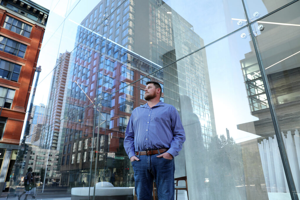 Man stands in a downtown location surrounded by tall buildings.