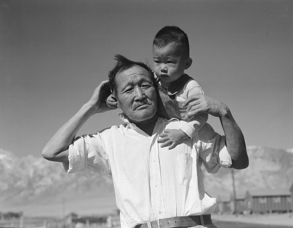 Black and white photo of a man with a child on his shoulders.