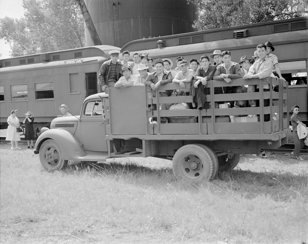 Black and white photo of a large group of people packed in a truck bed.
