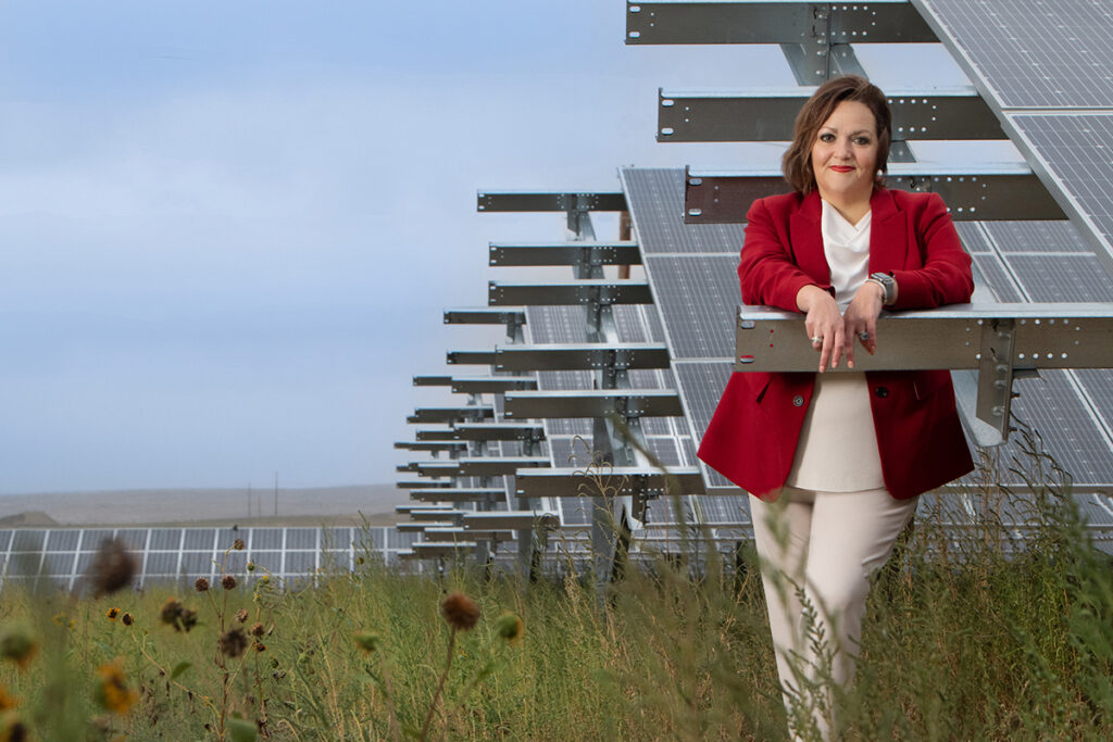 Woman stands in a field with solar panels.