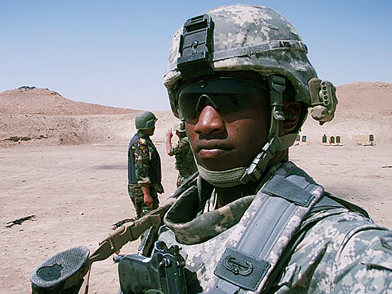 Man in combat gear in a desert setting.