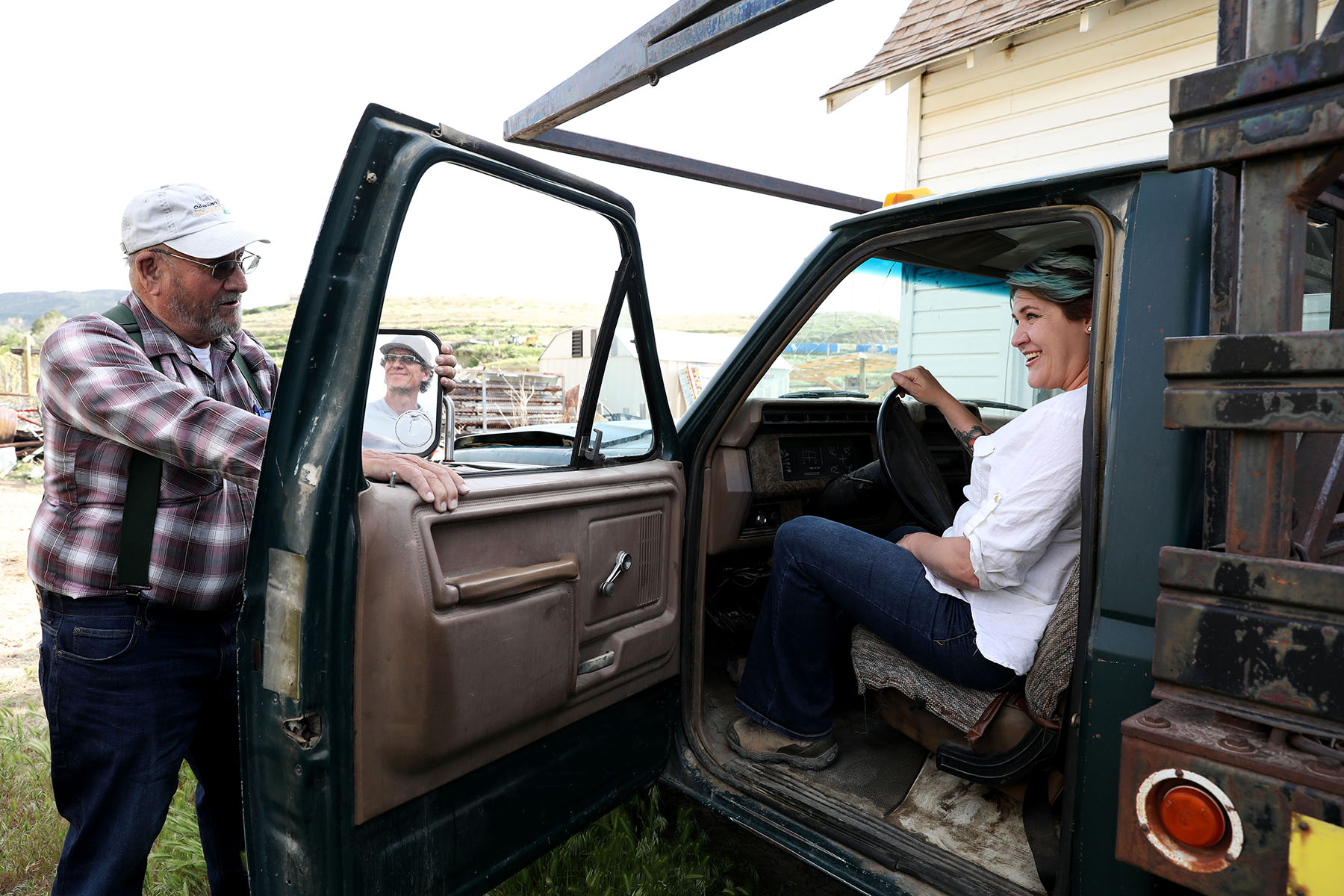 Two people converse through the open door of a truck.