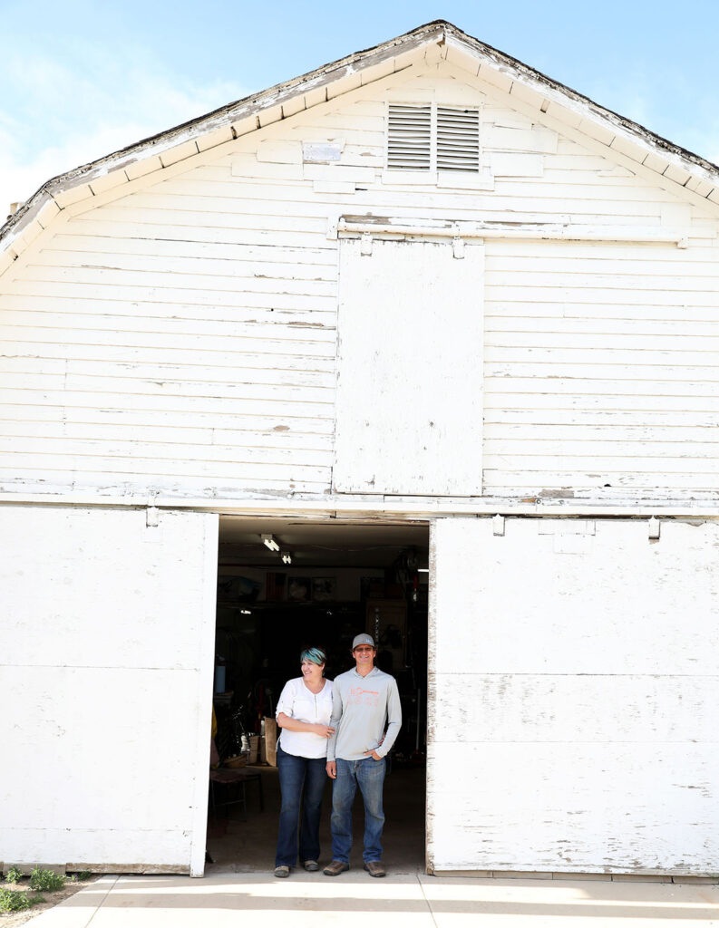 Two people stand in the doorway of a white barn.