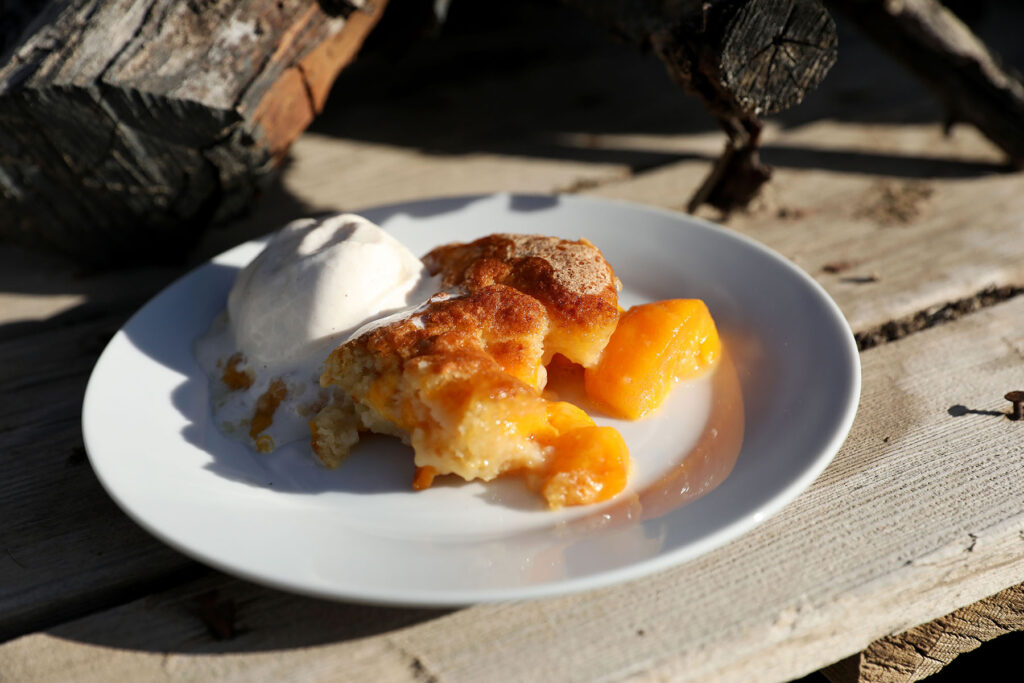 A plate of peach cobbler with a scoop of ice cream.