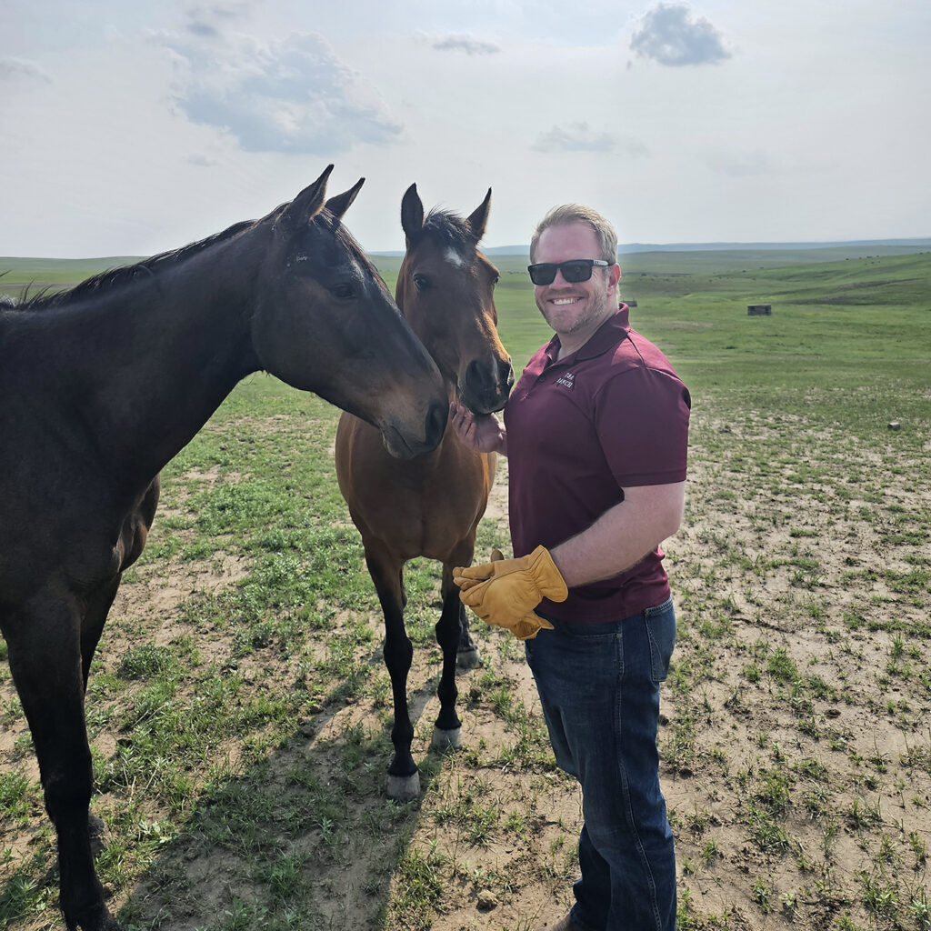 A man stands with two horses.