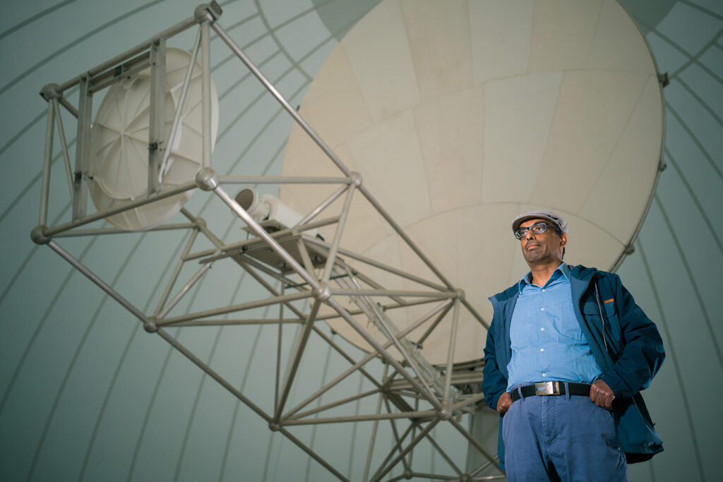 A man stands near a large satellite.
