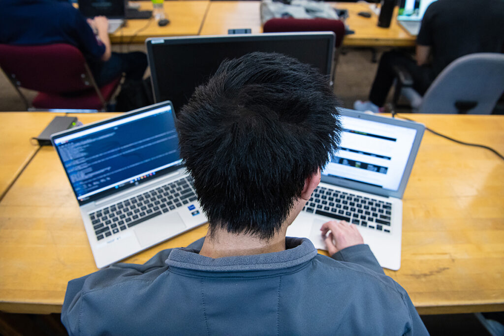 Top down view of a person working on two laptops.