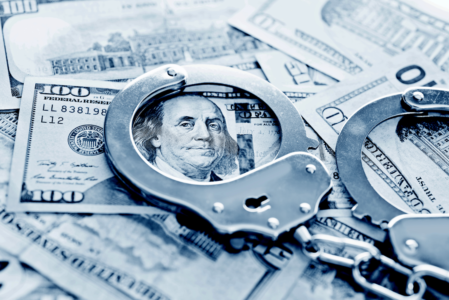 Stock image of handcuffs on a $100 bill.