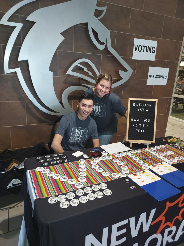 Two people work a booth with voting swag.