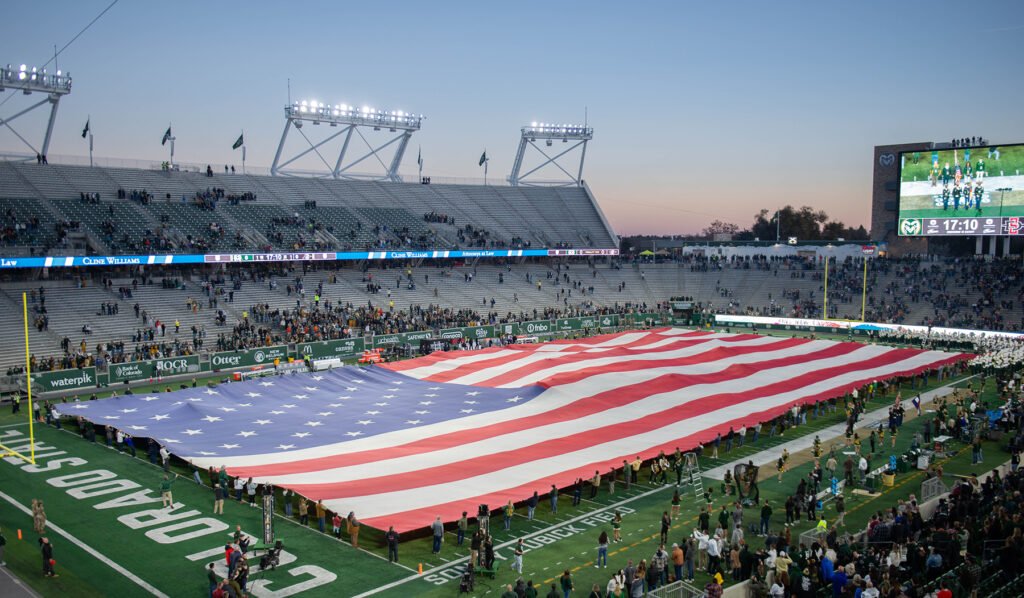 Aerial view of a large United States flag on a football field.