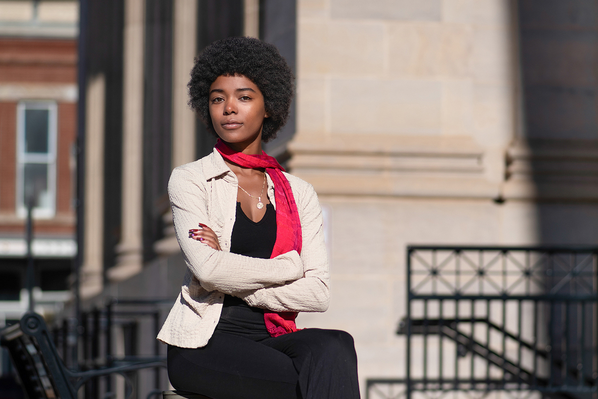 A woman poses in front of a stone building.