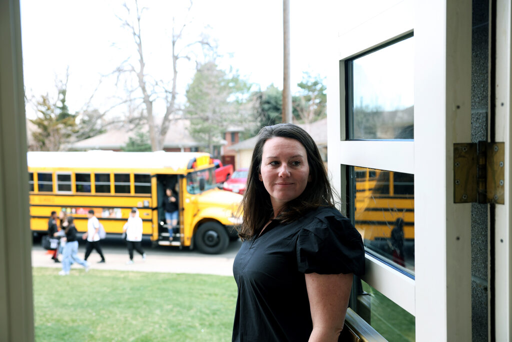 Woman standing in a doorway with school buses in the background.