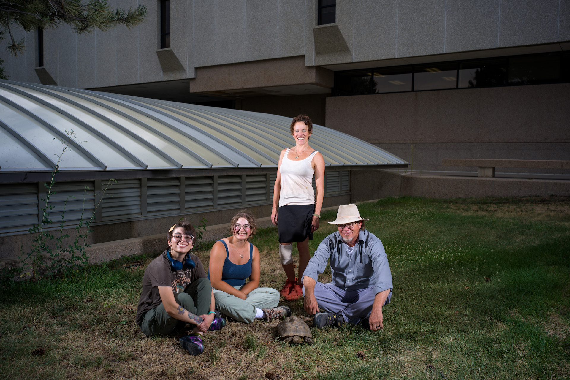 Group photo of four people and a tortoise.