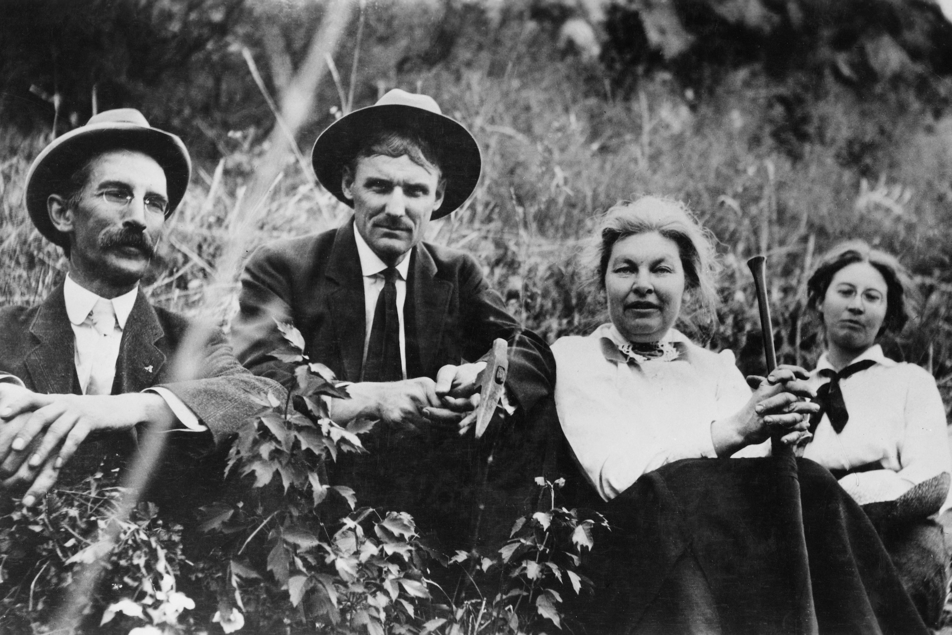 Historical photo of four people sitting together in a field.