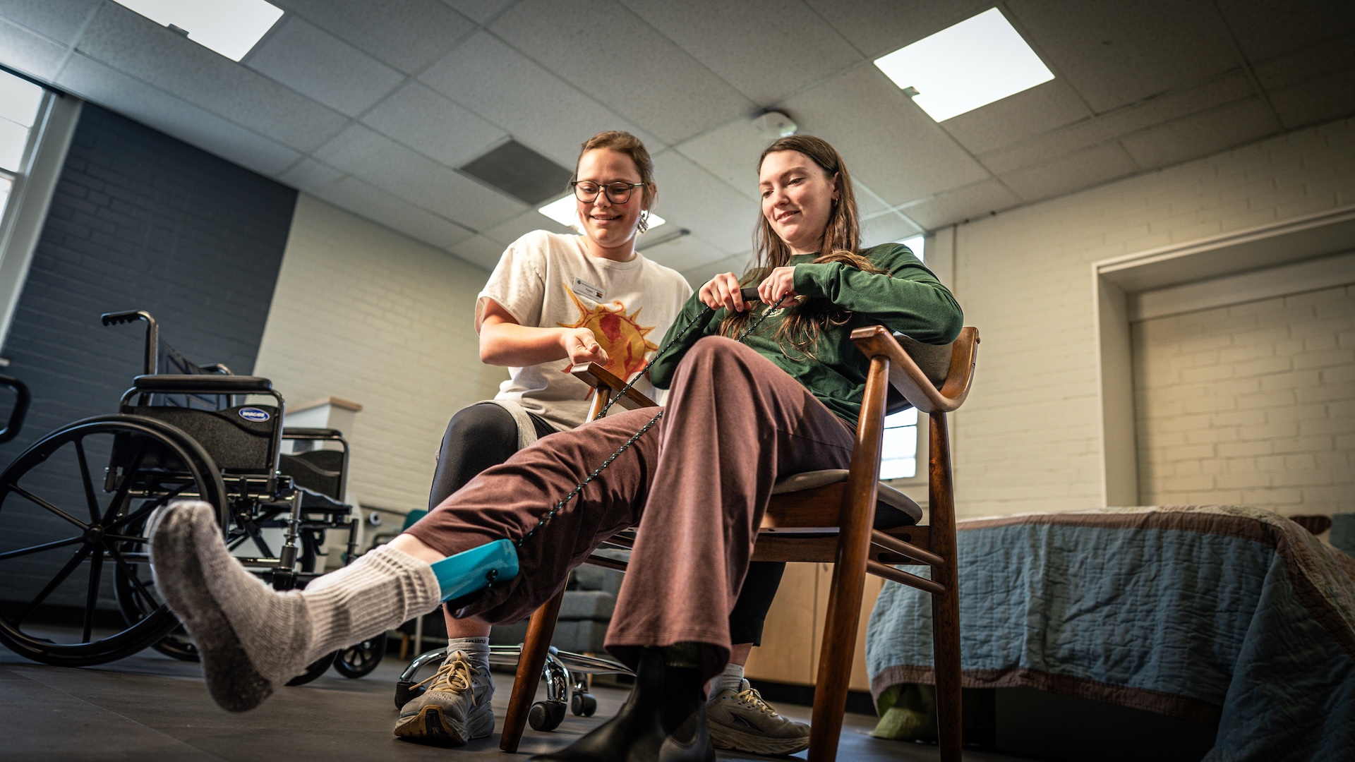 Two women work together on a foot exercise using rope and a handle.